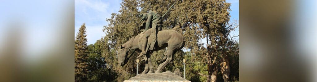 A statue of a man on horseback in the middle of a park.